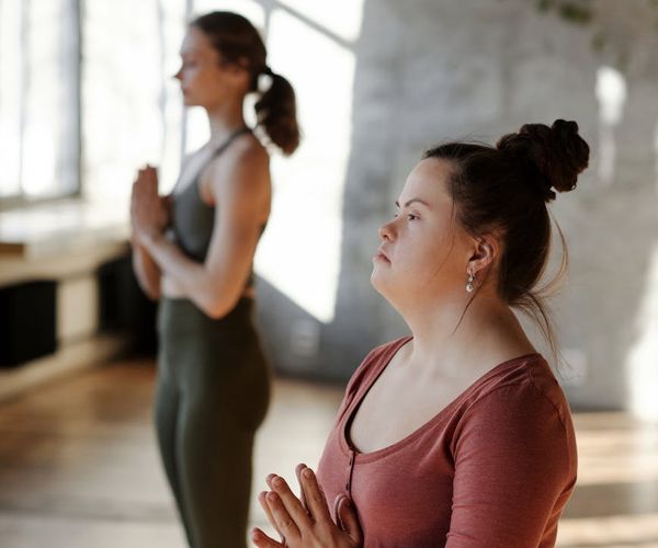Woman meditating peacefully in a bright, sunlit room.